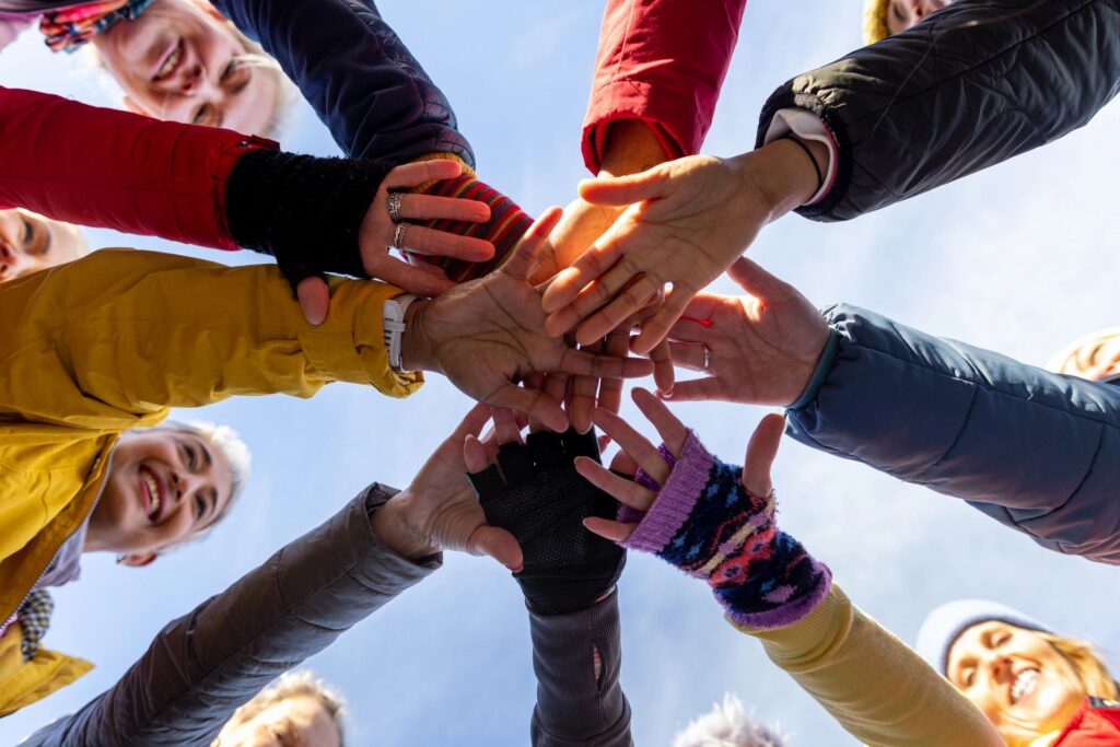 A group of people joining hands in a circle outdoors.