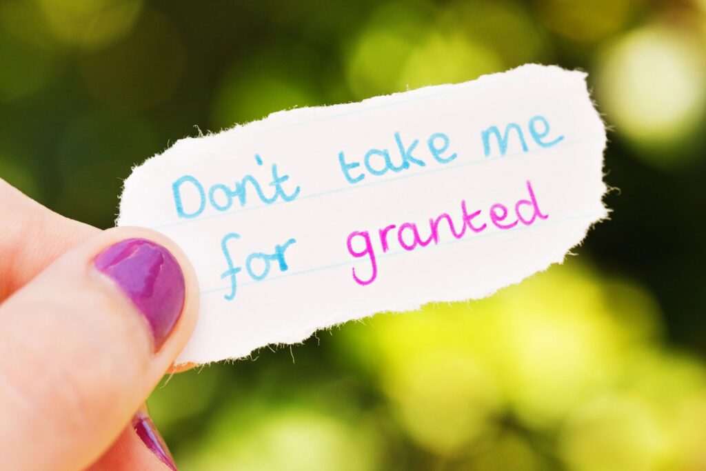 A hand holding a handwritten note that reads Don’t take me for granted.