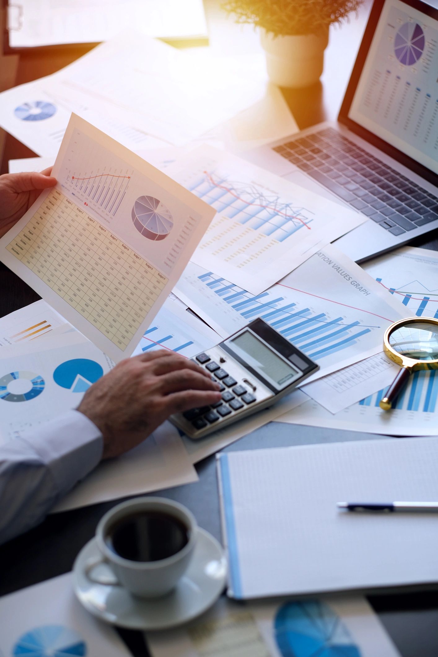 A person reviewing financial charts with a calculator and notebook.