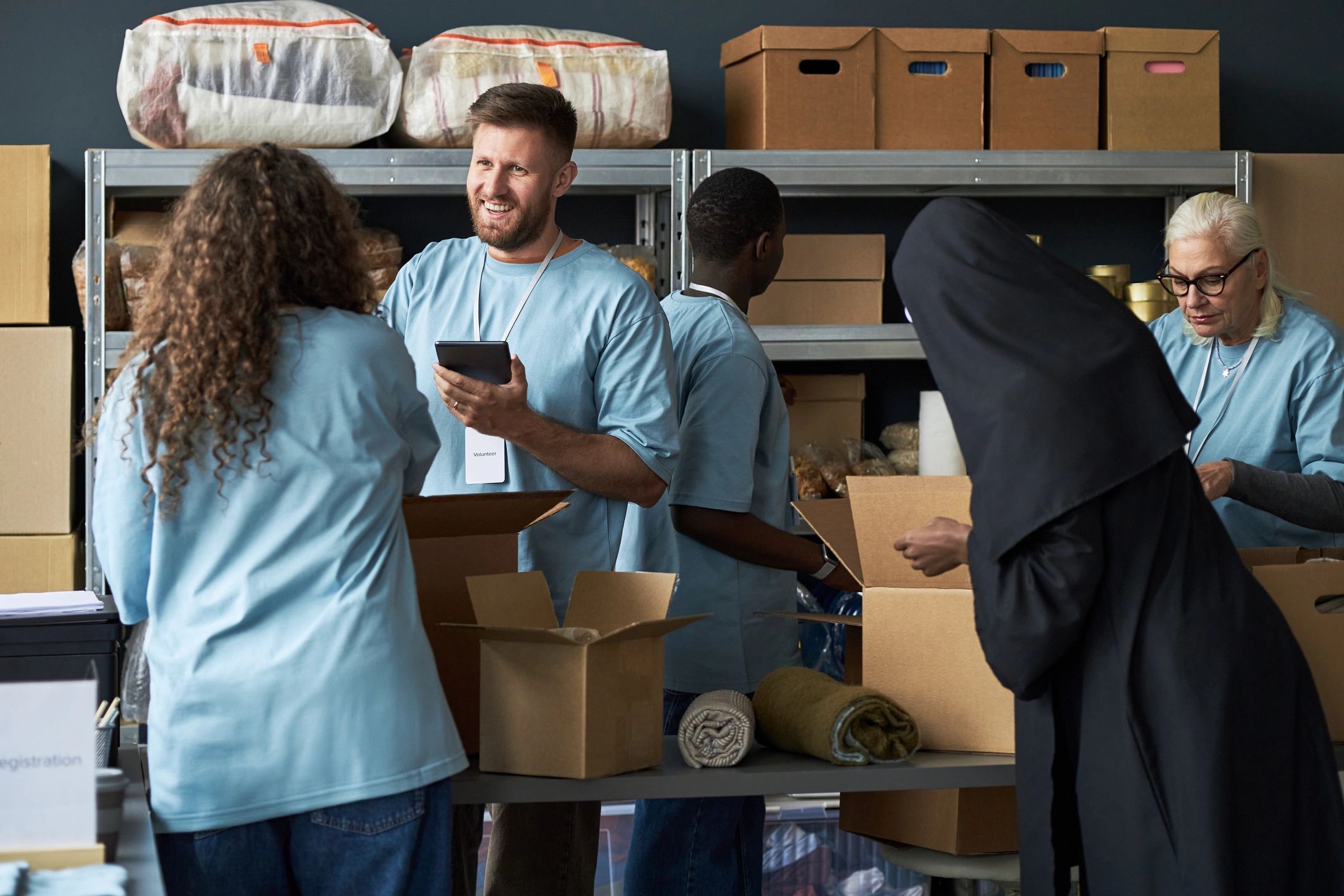 Volunteers sorting supplies and packing boxes in a storage room.