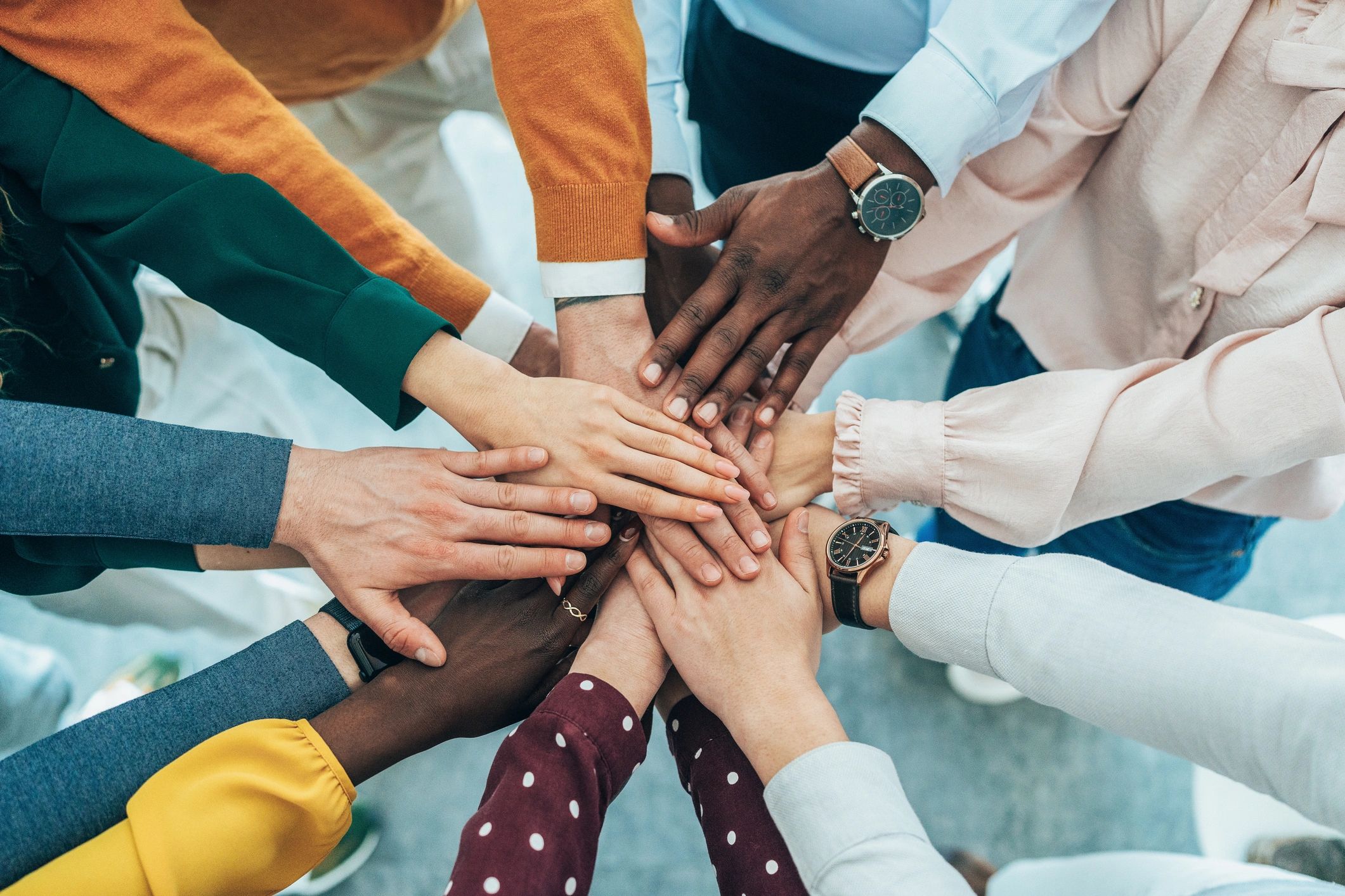 People stacking their hands together over a table.