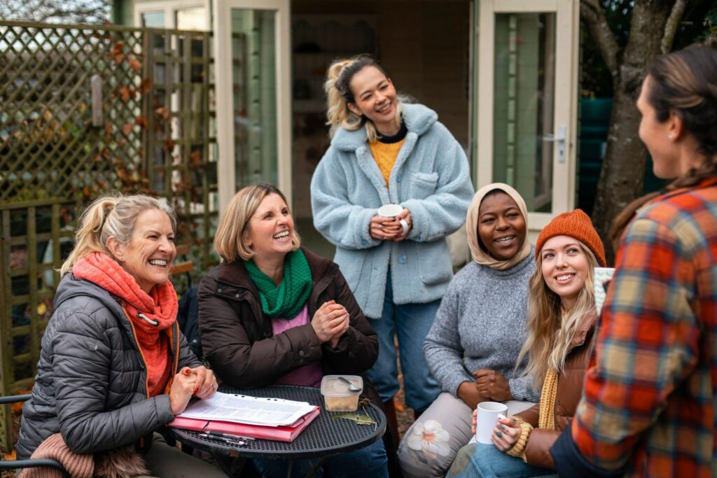 A group of people smiling and talking together around an outdoor table.