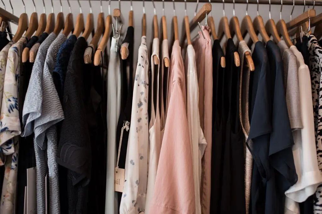 Clothing in neutral colors arranged on wooden hangers.