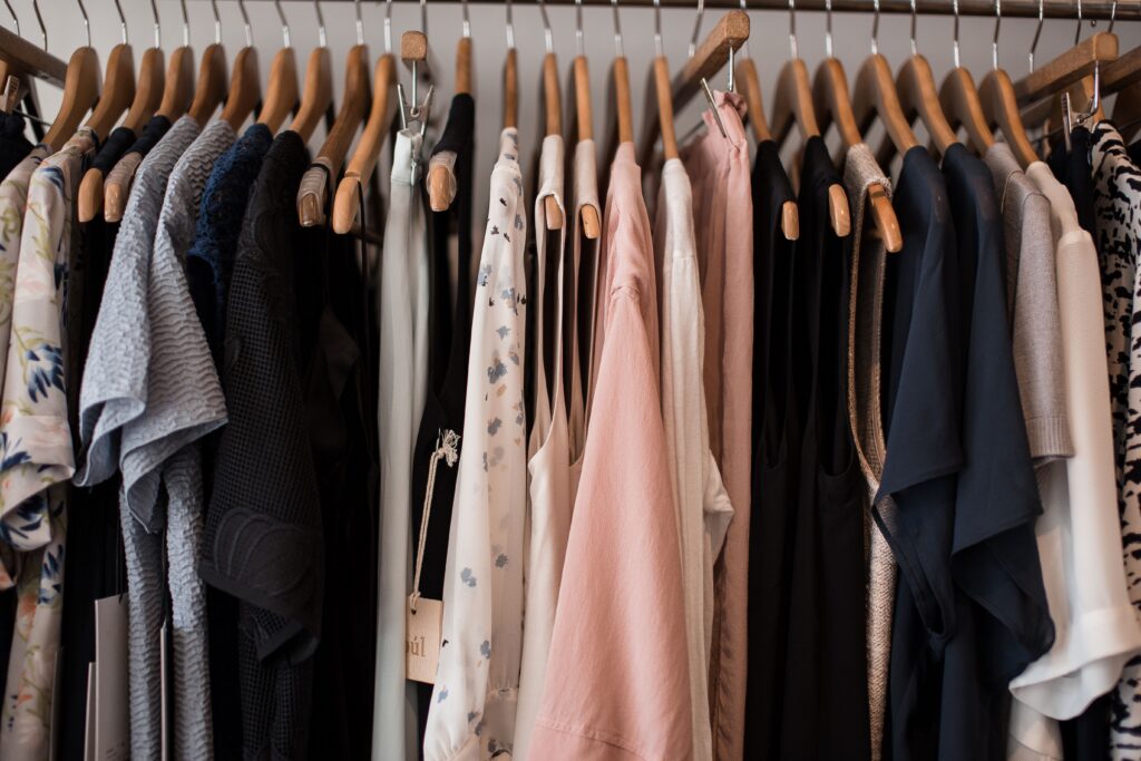 Clothing in neutral colors arranged on wooden hangers.